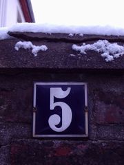 Hausnummer '5' an einer Mauer